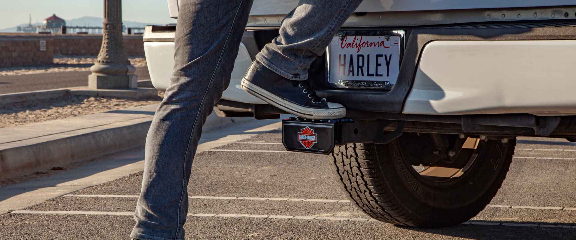 Person stepping onto a truck with a license plate that says "Harley" above a Harley Davidson Sticker